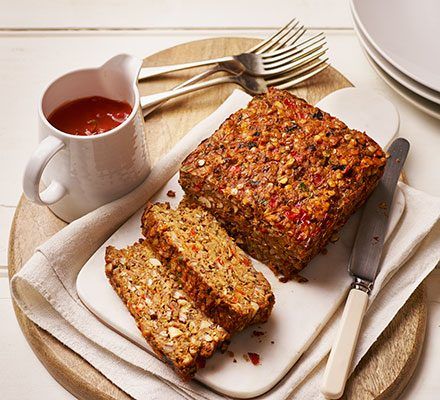 two slices of granola bread on a plate next to a cup of tea and silverware