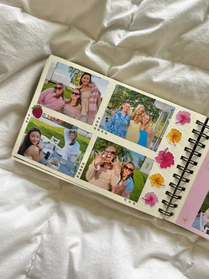 an open notebook with pictures of people on it sitting on a white bed sheet in front of a blanket