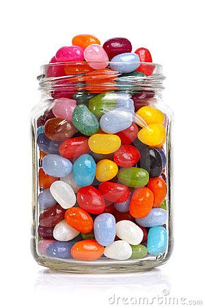 a glass jar filled with lots of colorful candies on top of a white surface