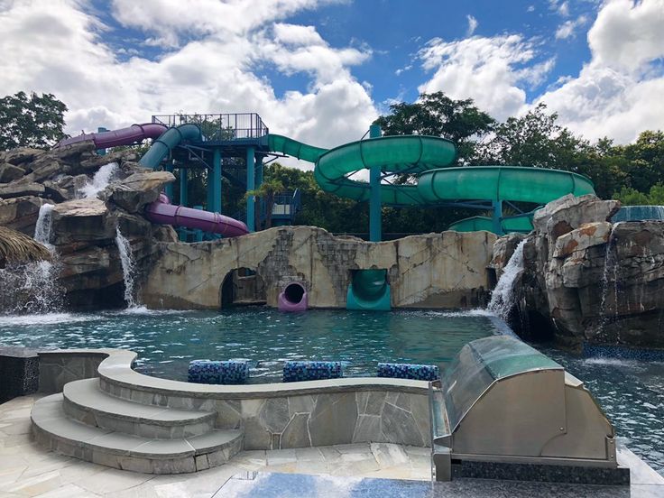 an outdoor swimming pool with slides and water features