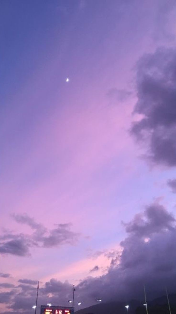 the sky is purple and blue with some white clouds in front of an empty parking lot