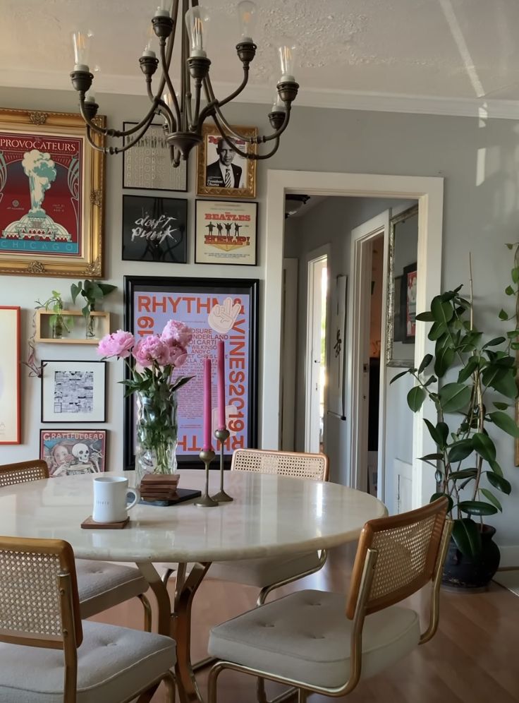 a dining room table with chairs and pictures on the wall