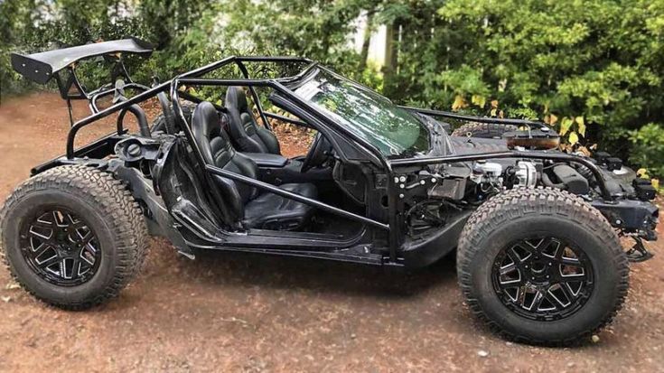 a buggy is parked on the side of a dirt road in front of some trees