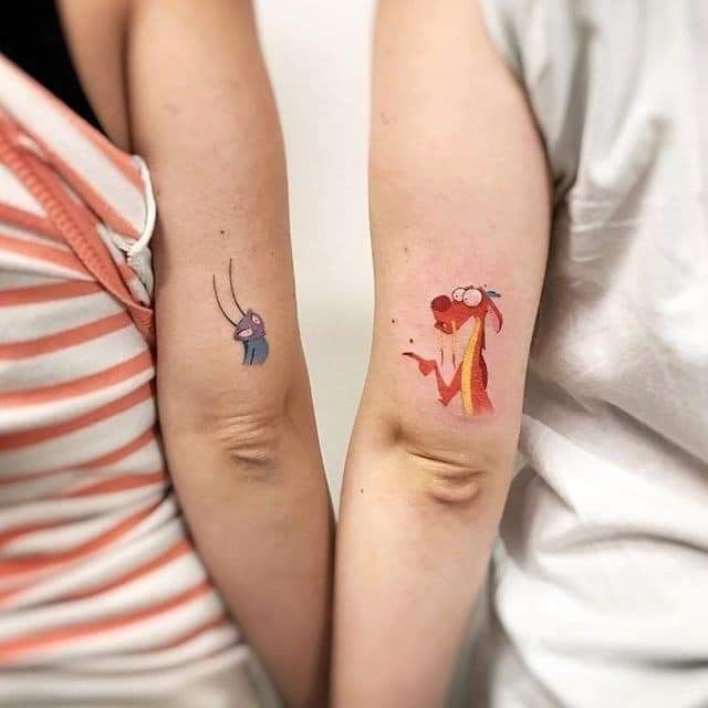 two people with matching tattoos on their arms, one has an elephant and the other has a giraffe