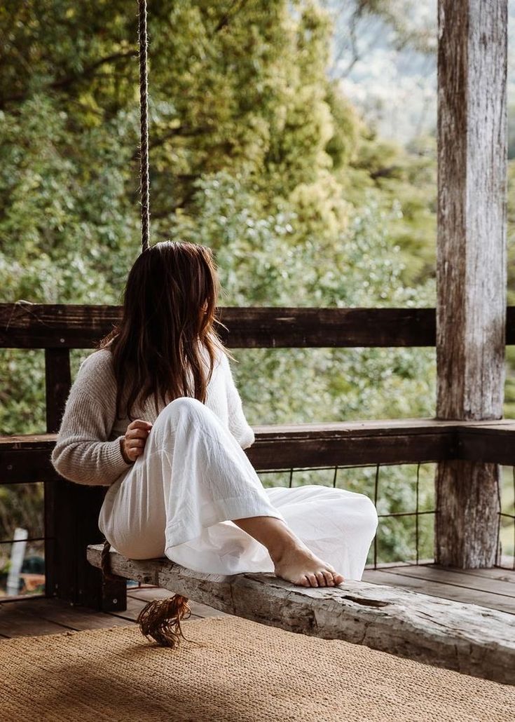 a woman is sitting on a porch swing