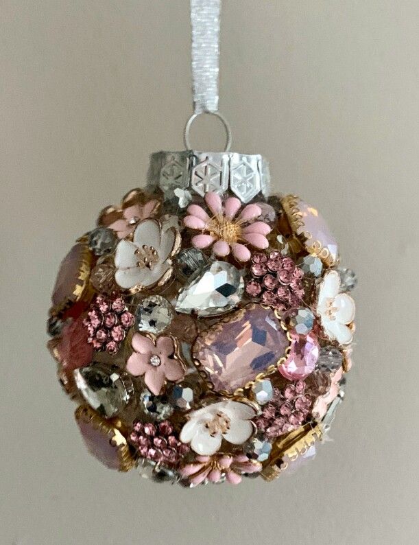 a ball ornament with flowers and jewels hanging from a string on a wall