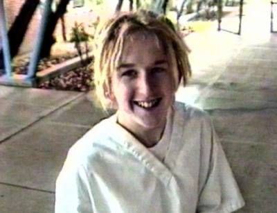 a young boy is smiling while sitting on the sidewalk