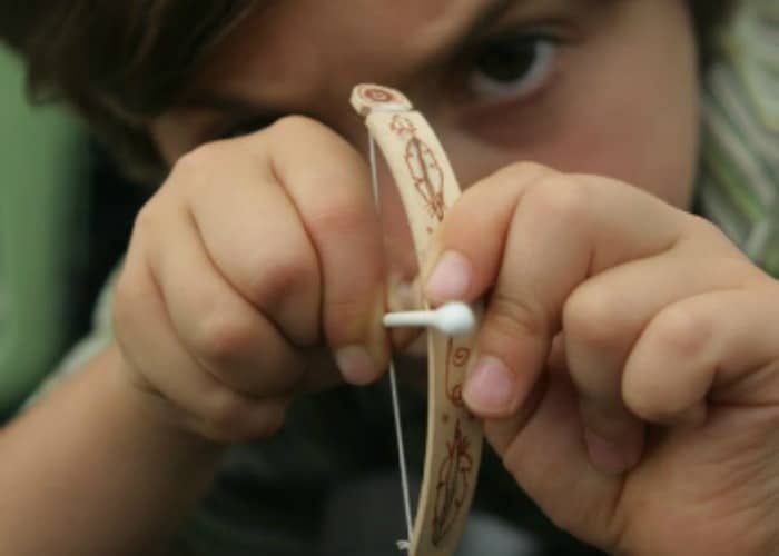 a young boy is playing with some type of object in front of his face and looking at the camera