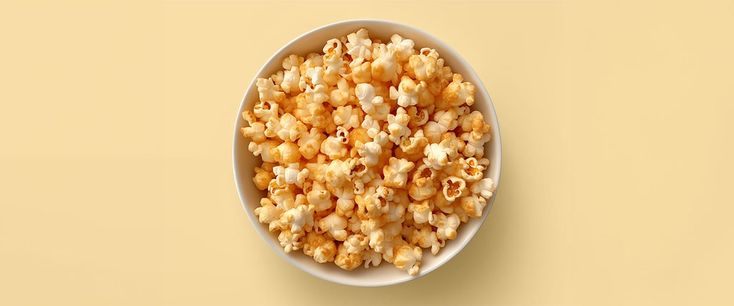 a white bowl filled with popcorn on top of a yellow table