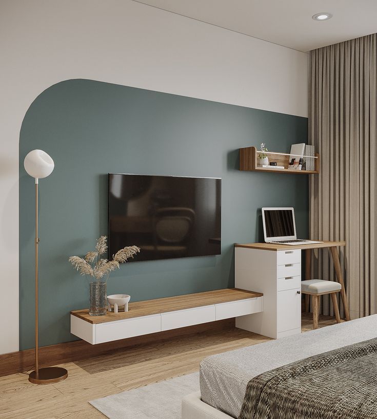 a bedroom with a bed, desk and television on the wall in front of it