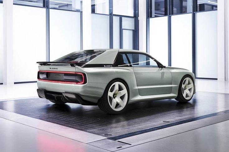 a silver sports car parked in front of large windows on a floor with an area rug