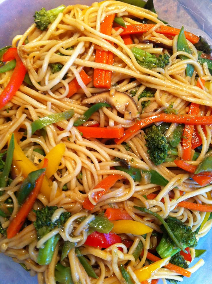 a bowl filled with noodles and vegetables on top of a table