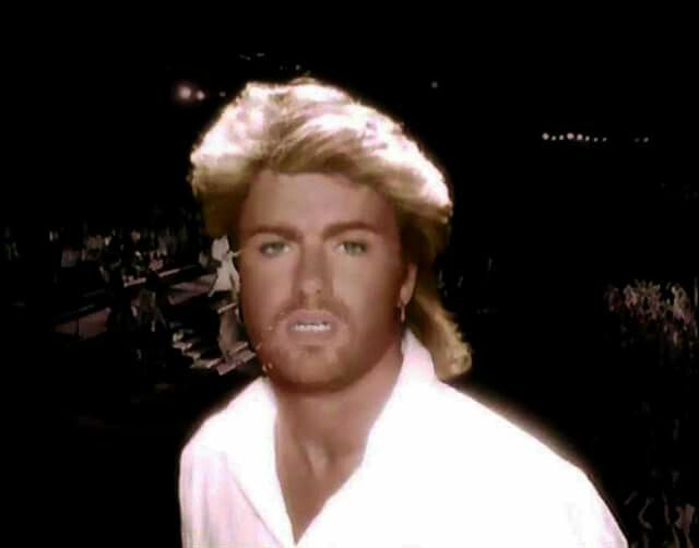 a man with blonde hair wearing a white shirt and looking at the camera while standing in front of an audience