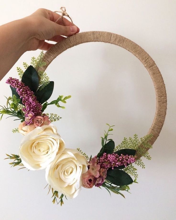 a hand holding a wreath with flowers and greenery