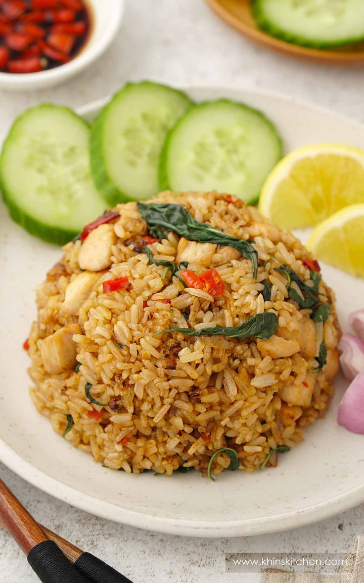 a white plate topped with rice next to cucumbers and lemon wedged slices