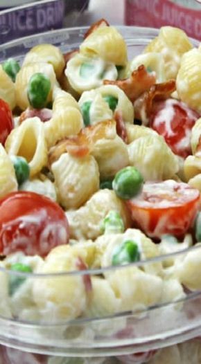 pasta salad with bacon, peas and tomatoes served in a glass bowl on an instagram page