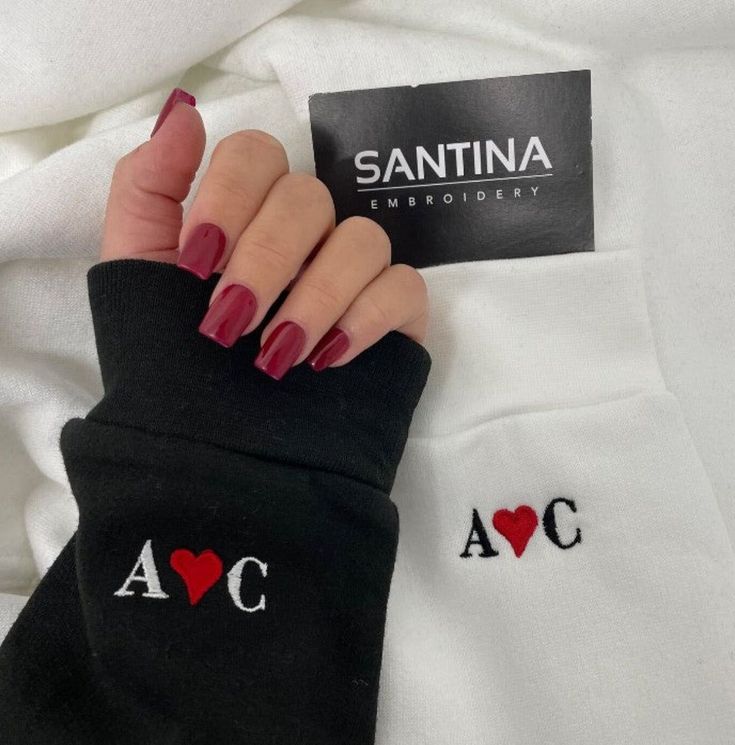 a woman's hand with red nail polish holding onto a white shirt that says, i love santa monica embroideryed on it