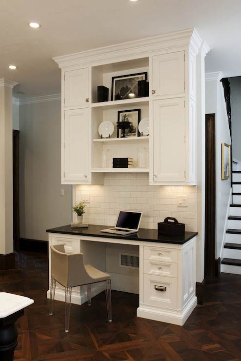 a home office with white cabinets and black counter tops, along with a staircase leading up to the second floor