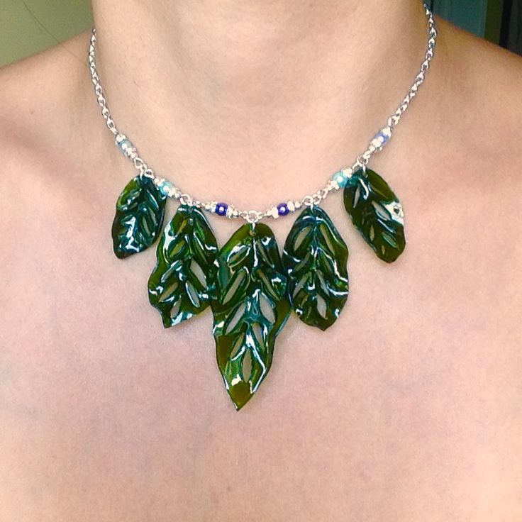 a woman wearing a green necklace with leaves on the front and back of her chest