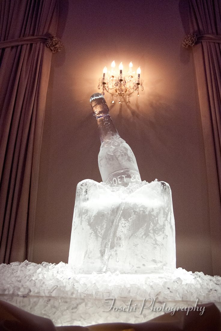 a large ice block with a bottle on top in front of a chandelier