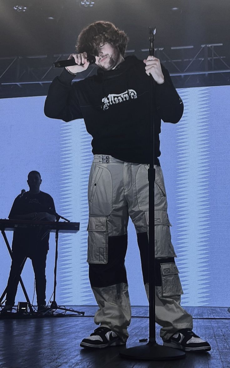 a man standing on top of a stage holding a microphone in front of his face