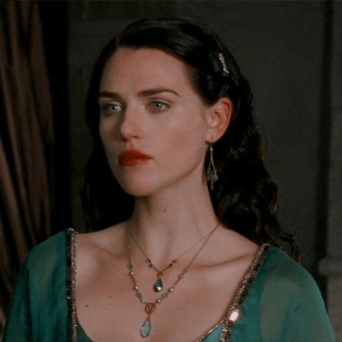 a woman in a green dress with necklaces and earrings on her neck, looking off to the side