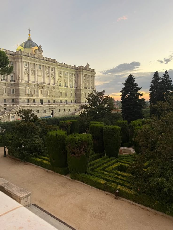 a large building with lots of trees in front of it and bushes on the side