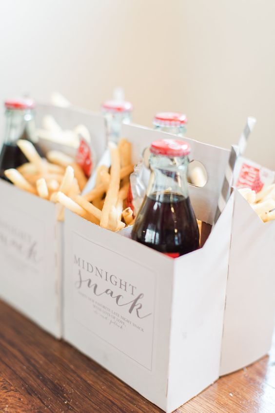 two bottles of soda and french fries in a white box on a wooden table top