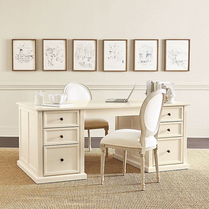 a white desk with two chairs and three pictures on the wall