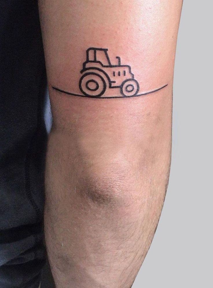 a man's arm with a small tractor tattoo on the left side of his leg