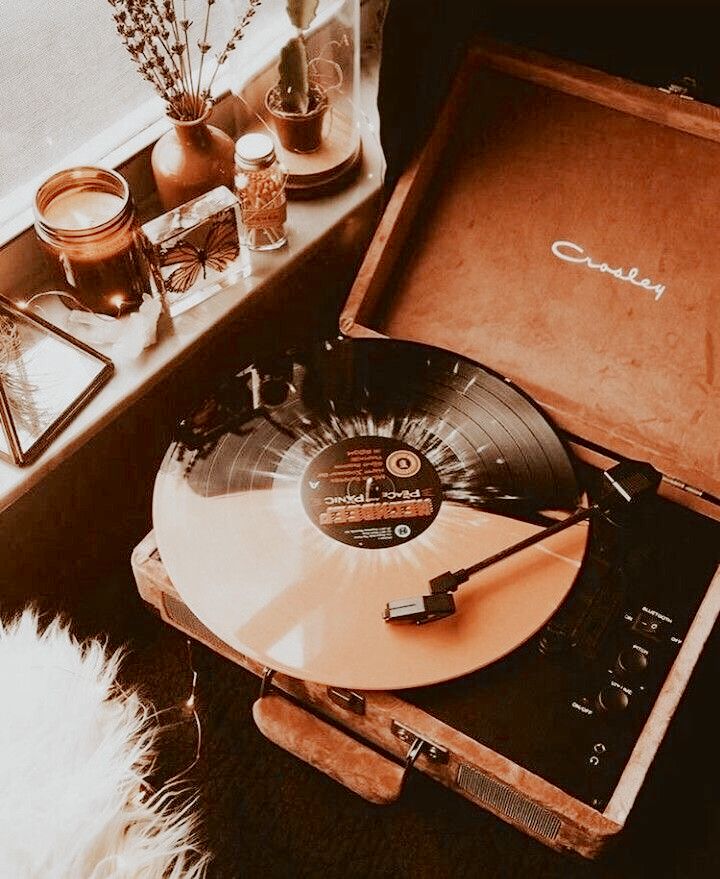 an orange record player sitting on top of a suitcase