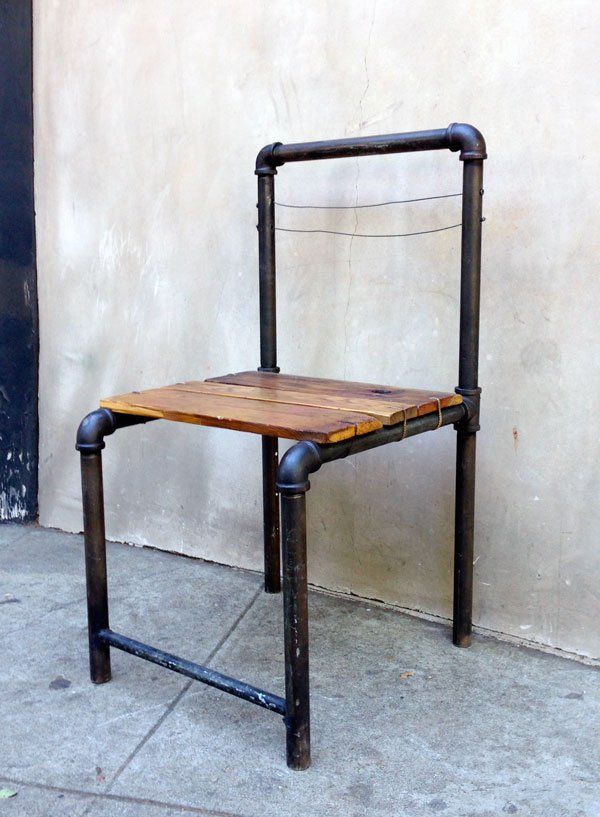 a wooden chair sitting on the sidewalk next to a building with metal frame and legs