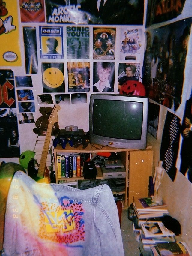 a television sitting on top of a wooden stand next to a wall covered in pictures