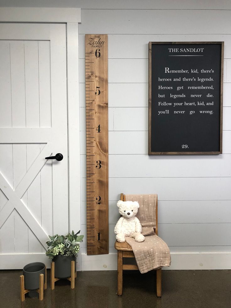 a teddy bear sitting in a chair next to a growth chart