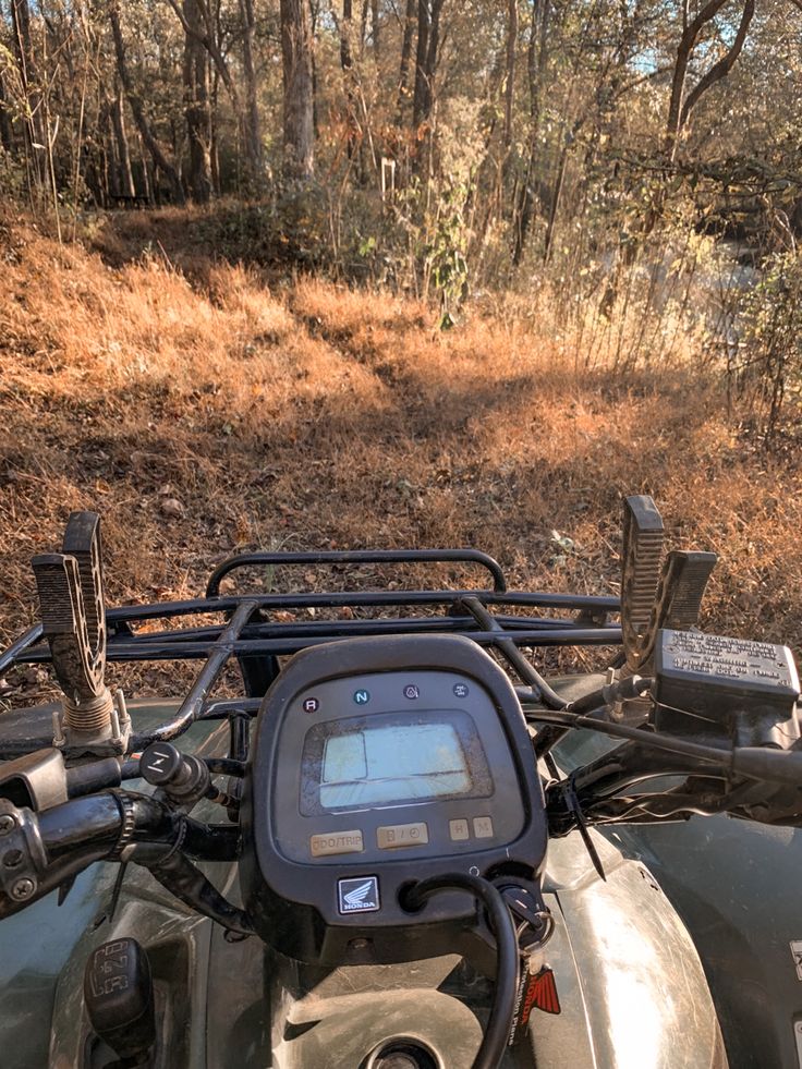 a motorcycle with a gps on the handlebars is parked in front of a wooded area