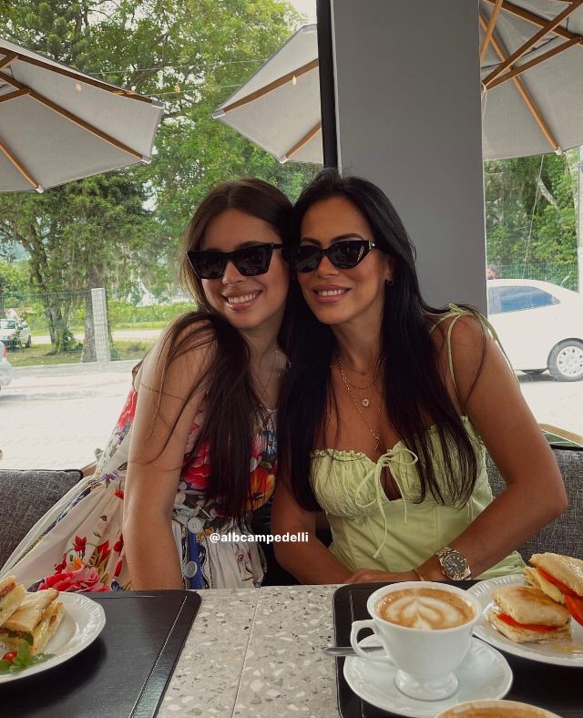 two beautiful women sitting at a table with food