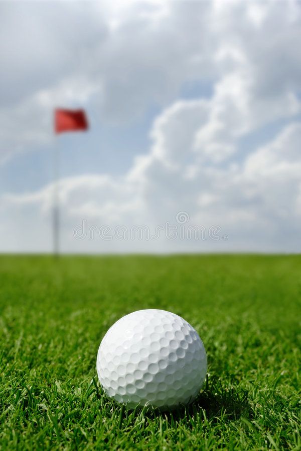 a golf ball sitting in the grass next to a red flag on a green field