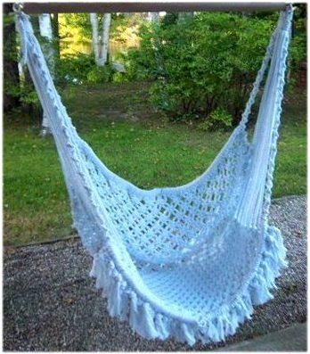 a white crocheted hammock hanging from a tree