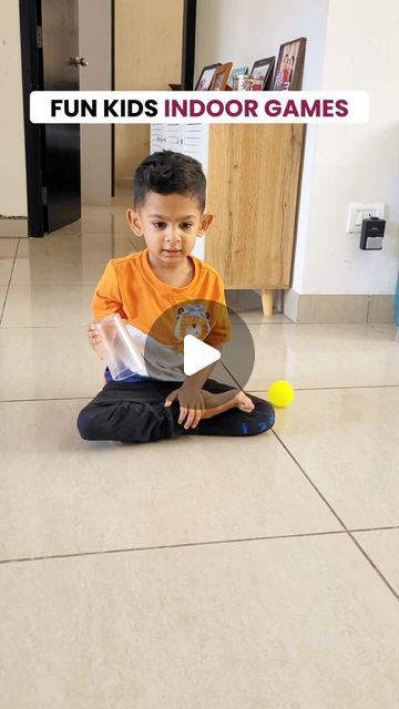 a young boy sitting on the floor playing with a ball