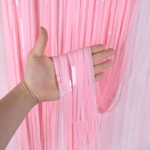 a hand is holding onto pink sheer curtains