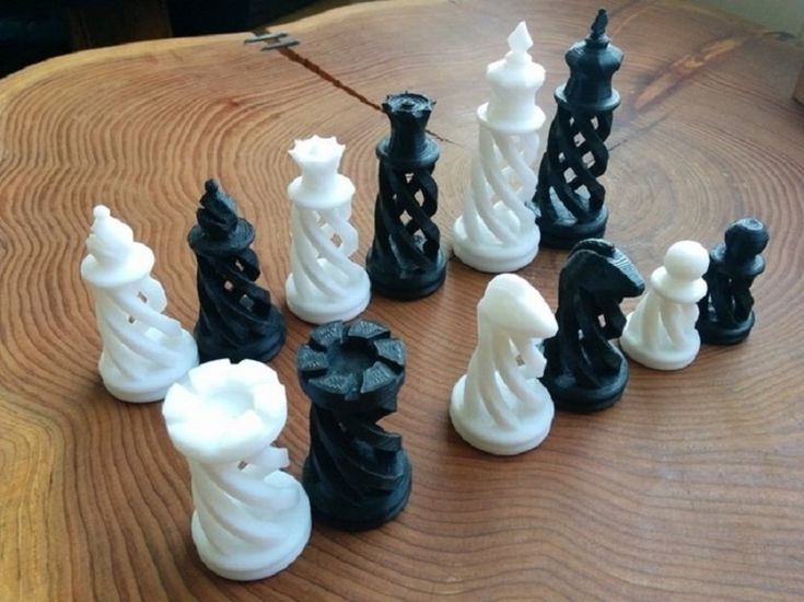 a chess set made out of black and white plastic pieces on a wooden table top