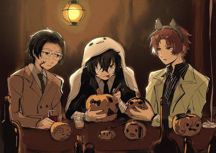 three people sitting at a table with pumpkins