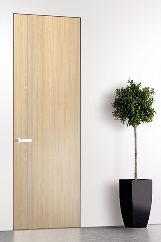 a potted plant sitting next to a wooden door in a white room with an empty wall