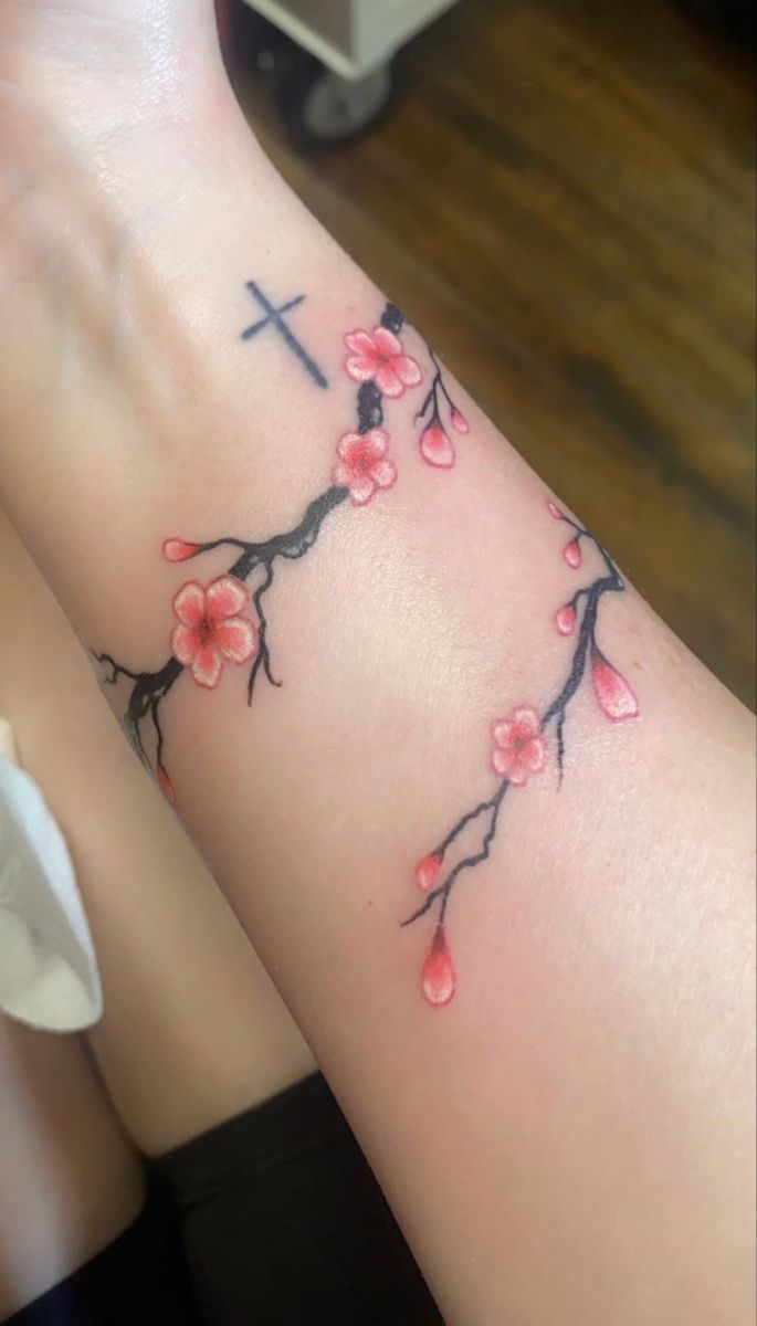 a woman's arm with a cross and flowers on it