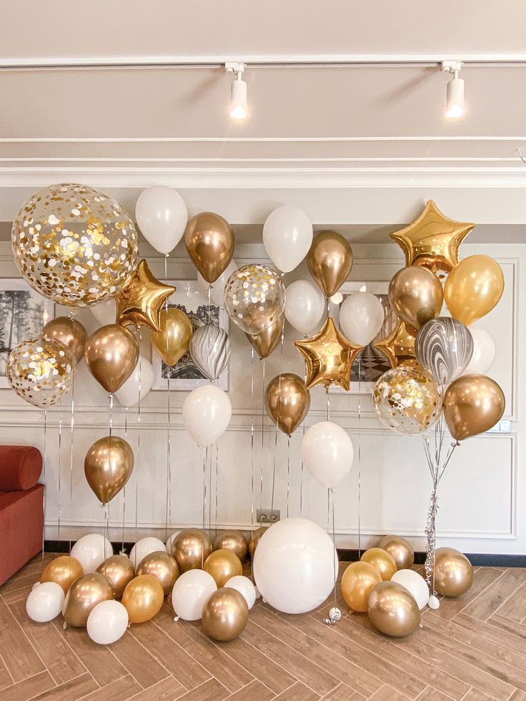 gold and white balloons are hanging from the ceiling