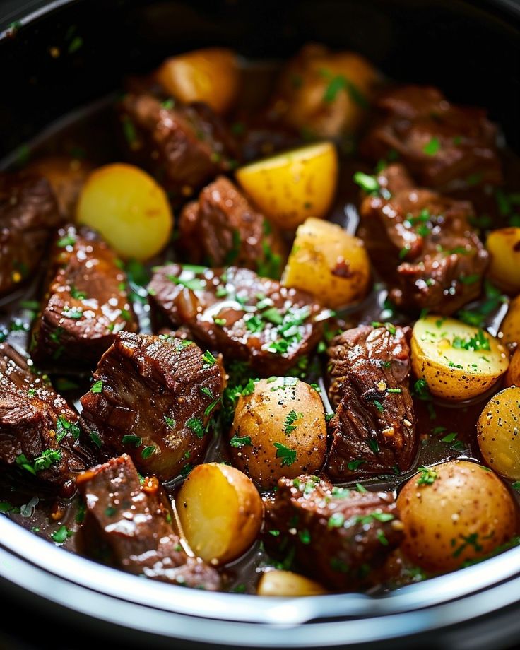 a pot full of beef and potatoes with parsley