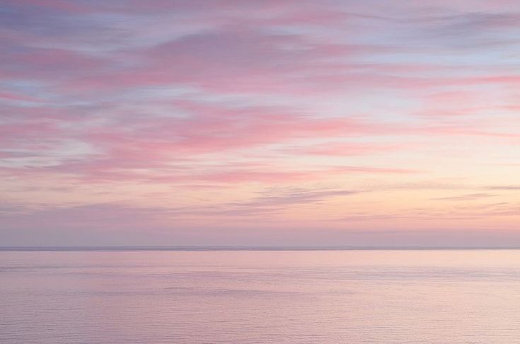 the sky is pink and purple as it reflects in the water