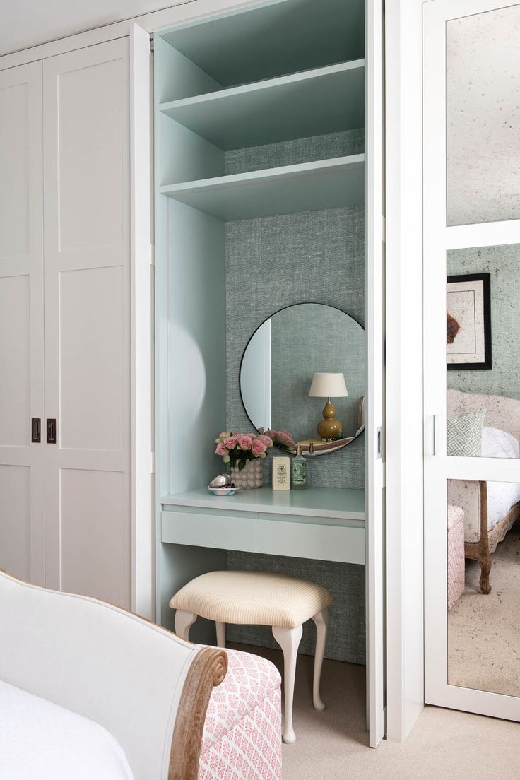 a bedroom with a dressing table, mirror and stool next to the closet door that is open