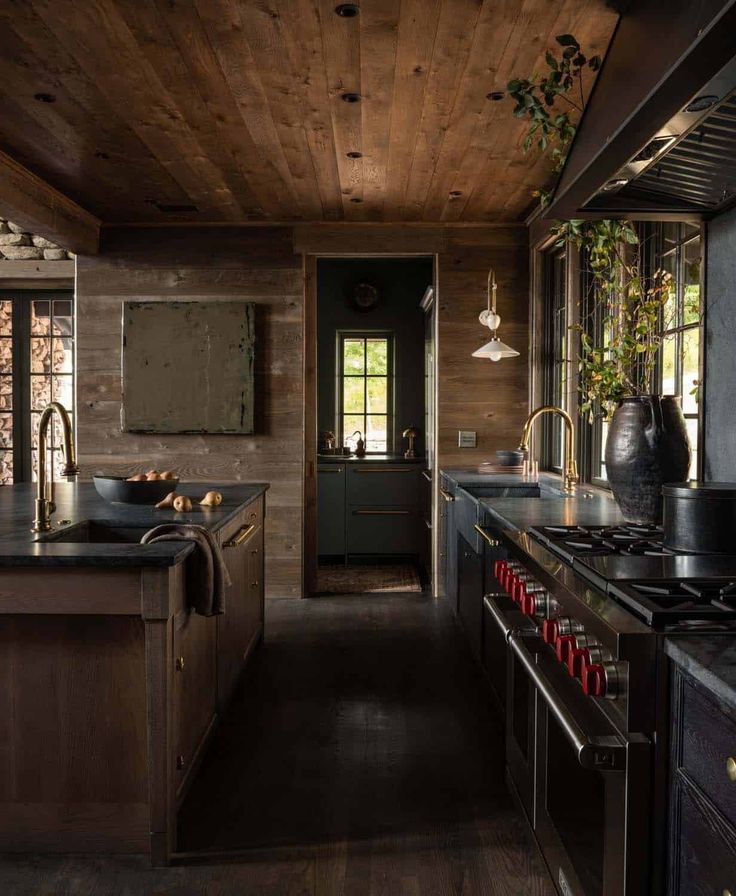 a kitchen with dark wood floors and wooden walls, along with black counter tops on both sides