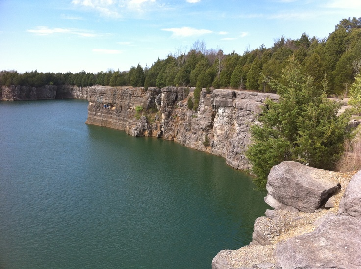 a large body of water surrounded by rocks and trees on the side of a cliff